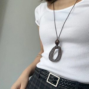 Detailed macro view of the irregular brown resin ring pendant on a long rope necklace