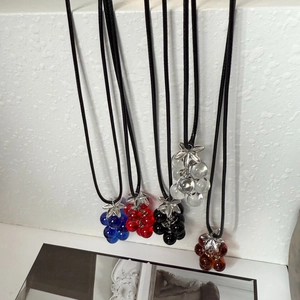Close-up of colorful glass grape pendants on black cords in various vibrant shades