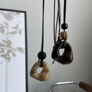 Detail of minimalist resin pendant necklaces with wooden beads on long brown cords