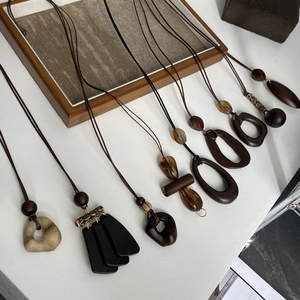 Detailed view of bohemian style brown resin pendants and tassel necklaces on a wooden tray