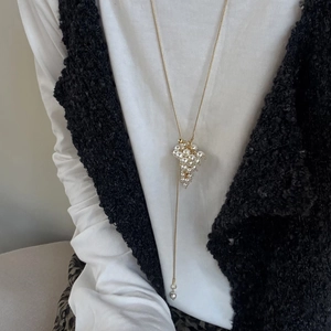 Close-up of golden Y-shaped necklace featuring a pearl grape cluster pendant on model