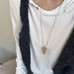 Close-up of golden grape cluster pendant with metallic sphere design on long chain