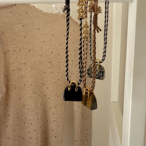 Detailed shot of miniature handbag pendants with tiger eye stone and woven tassel cords