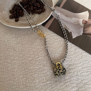Detail of hand-woven three-color cord necklace with natural dalmatian stone pendant