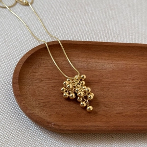 Elegant gold necklace featuring a grape cluster pendant of polished beads on a snake chain