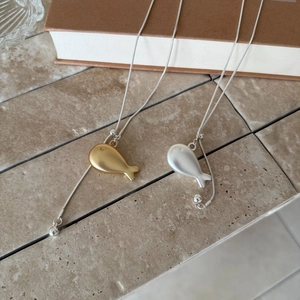 Detail of cute gold and silver fish pendants with minimalist snake chain necklaces