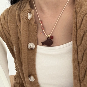 Detail of hand-woven cord necklace featuring a dark brown fish charm and a red agate bead