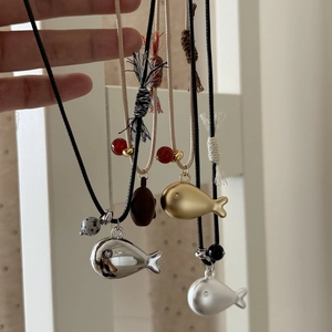 Detail of colorful fish pendants with woven cords and decorative beads on hand