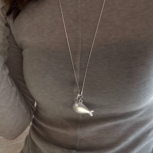Close-up of minimalist silver whale pendant on a snake bone chain for women