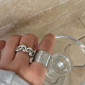 Detailed close-up of chunky chain link and multi-layer silver hollow rings on a hand
