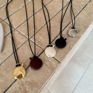 Macro detail of oval pendant necklaces in gold, burgundy, silver, and black finishes