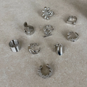 Detailed view of silver hollowed geometric rings and earrings with woven textures