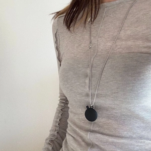 Minimalist oval black pendant necklace paired with grey slim fit knitted sweater