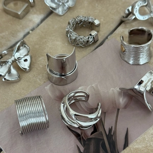 Detail of silver plated geometric hollow rings and butterfly earrings on marble background