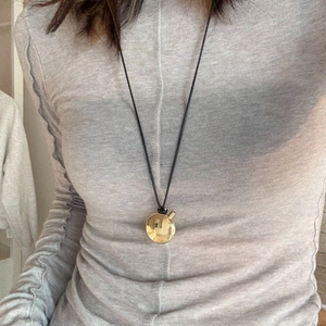 Minimalist gold ball pendant necklace with black cord on grey sweater outfit