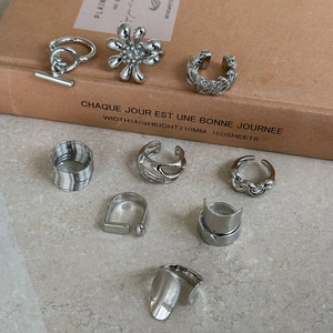 Close-up of assorted silver-tone rings and earrings with diverse geometric textures