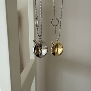 Detail view of mirror-polished gold and silver spherical pendants on delicate chains
