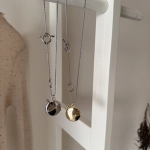 Detail of oval pendant necklaces in gold and silver finish with toggle clasp design