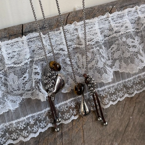 Detail von böhmischen Wassertropfen-Anhängern mit Tigerauge auf altem Holz und Spitze