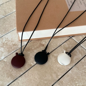 Minimalist oval pendant necklaces in matte red, black, and silver with woven cords