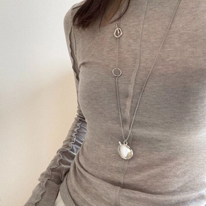 Detailed view of silver minimalist long oval pendant necklace on a knit sweater