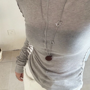 Close-up of a silver-toned long necklace with OT clasp and matte red apple pendant