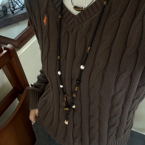 Detail einer langen Perlenkette aus Achat und Tigerauge auf braunem Strickpullover