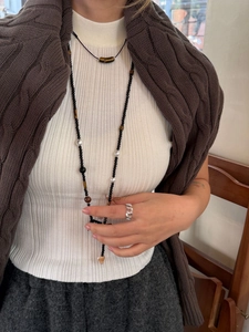 Detail einer langen Achat- und Tigerauge-Perlenkette an Modell in Herbstpullover