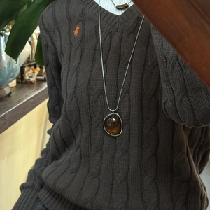 Irregular amber resin pendant necklace with silver chain on vintage brown sweater