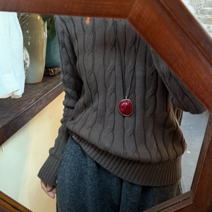 Macro view of a deep red resin oval pendant with a minimalist black cord sweater chain