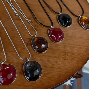Detail view of irregular resin pendants on wooden background with varied chain styles