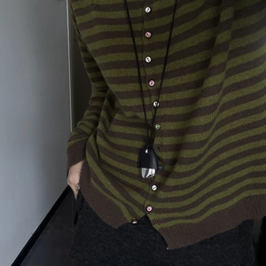 Fashionable leather and metal pine cone pendant necklace with green striped cardigan