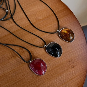 Detailed macro view of resin irregular oval pendants in amber black and deep red colors