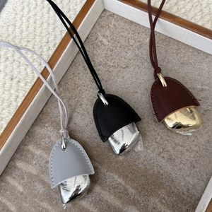 Detail of leather clochette necklaces with metallic pendants on a wooden tray