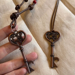Detail of vintage bronze heart key pendant with floral butterfly pattern on woven cord