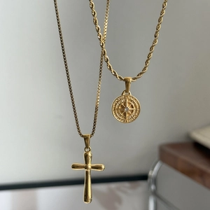 Dettaglio dei ciondoli a croce e bussola placcati in oro 18K su due catene diverse