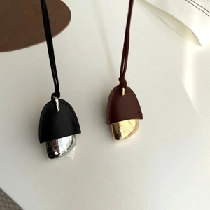 Detailed view of minimalist leather and metal pinecone pendant necklaces in black and brown