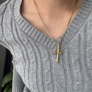 Collana con pendente a croce in oro 18K lucido su modella con maglione grigio