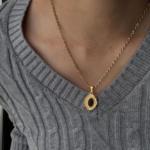 Dettaglio di una collana in acciaio inossidabile placcato oro 18K con ciondolo in pietra nera