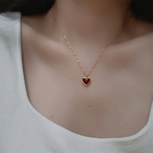 Minimalist gold necklace with red heart-shaped agate pendant worn by female model