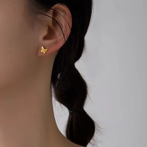 Primer plano de pendiente de mariposa dorada con textura cepillada en la oreja del modelo