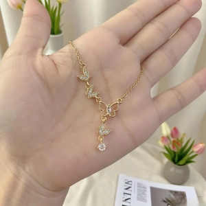 Elegant gold butterfly tassel necklace with sparkling zircon crystals held in hand