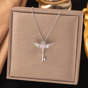 Detailed close-up of s925 silver wing key pendant with pink heart zircon in a jewelry box