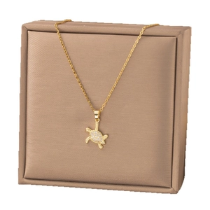 Élégant collier pendentif tortue en or avec cristaux de zircone sur une boîte à bijoux en satin