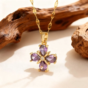 Macro detail of teardrop purple zircon clover pendant with gold textured chain links