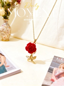 Detail of red rose pendant with gold stem and zircons on a warm textured background