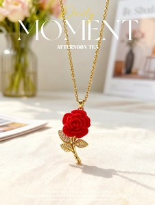 Macro shot of red rose pendant with gold leaves and micro-pave zircons on a gold chain