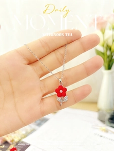 Close-up of red matte flower pendant with zircon core and sparkling silver leaf details
