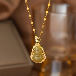Makroaufnahme der Goldhalskette mit Jade-Anhänger, glänzenden Zirkonen und Münze