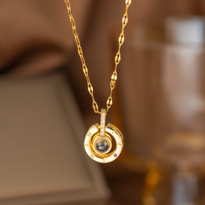 Detail of gold titanium necklace pendant with Roman numerals and red gemstone accent